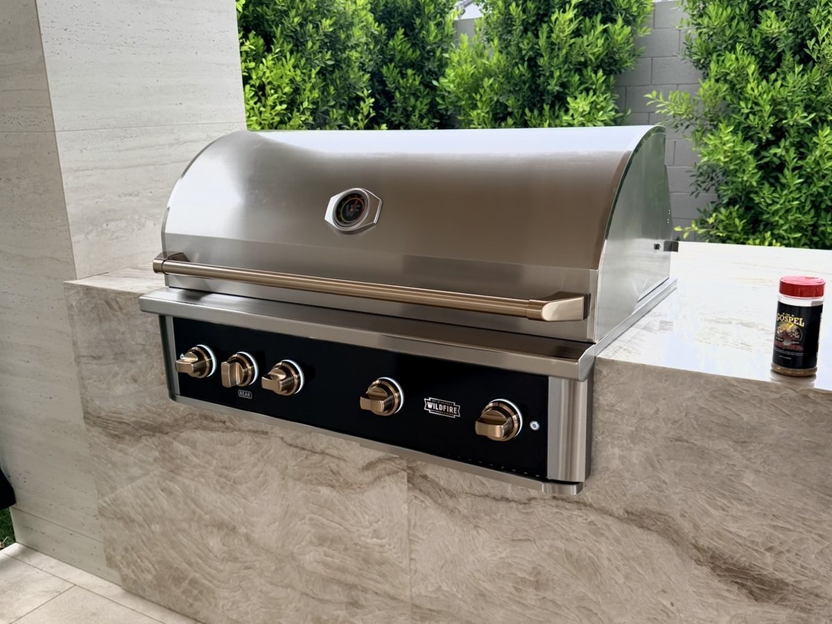 A Wildfire built-in gas grill in black stainless set into a finished stone island